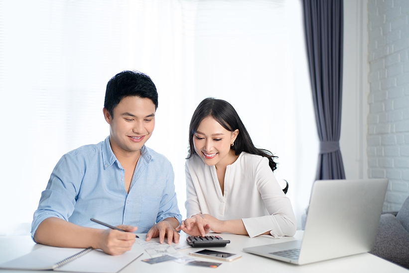 Asian couples are calculating their expenses with a calculator. They are happy.